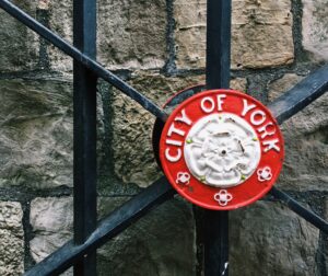 Weathered stone wall with dark wooden lattice; a red circular sign partially visible at the edge.